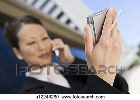 Young businesswoman using mobile and PDA View Large Photo Image Stock Image - Young businesswoman using mobile and PDA. Fotosearch