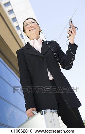 Stock Image - Young businesswoman using mobile outdoors, portrait. Fotosearch