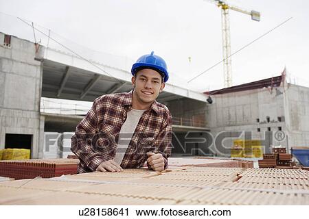 Stock Image - Young construction worker on building site. Fotosearch