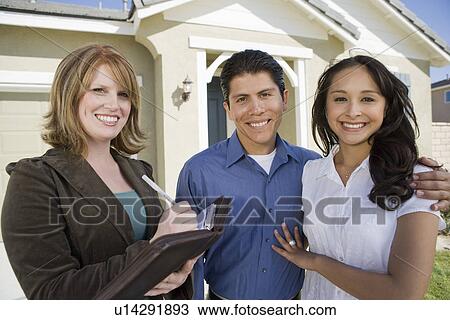 Stock Image - Young couple buying house, signing contract. Fotosearch