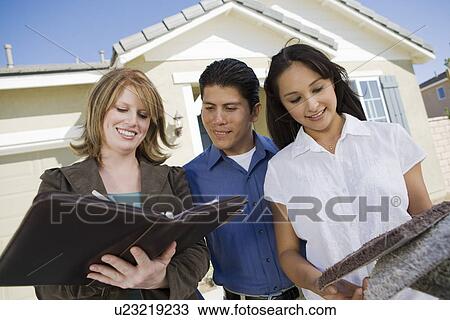 Stock Image - Young couple buying house, signing contract. Fotosearch