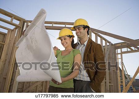 Young couple examining blueprint in construction site View Large Photo Image Stock Photography - Young couple examining blueprint in construction site. Fotosearch