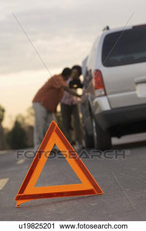 Young couple leaning on car behind warning triangle View Large Photo Image Stock Image - Young couple leaning on car behind warning triangle. Fotosearch