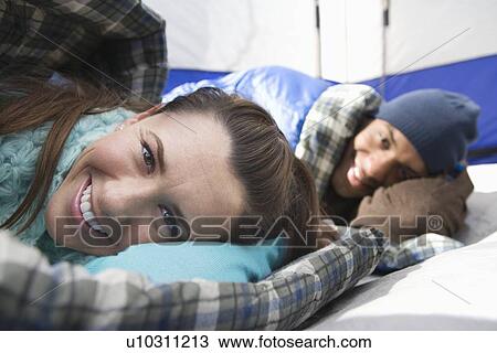 Stock Image - Young couple lie in sleeping bags in a tent. Fotosearch