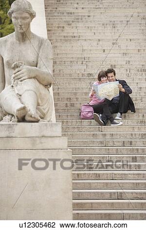 Young couple looking at map sitting on stairway View Large Photo Image Stock Image - Young couple looking at map sitting on stairway. Fotosearch