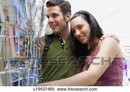 Young couple looking at postcards, portrait View Large Photo Image Stock Photography - Young couple looking at postcards, portrait. Fotosearch