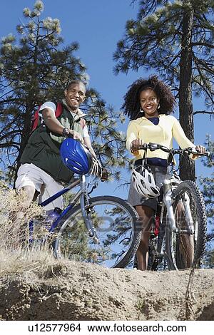Picture - Young Couple Mountain Biking, low angle view.. Fotosearch