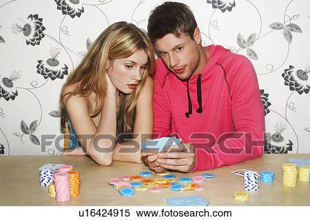 Stock Photography - Young Couple playing cards looking at hand together. Fotosearch