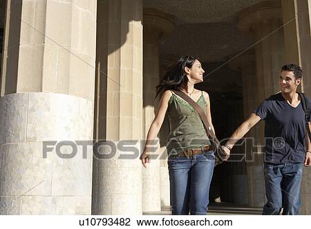 Stock Image - Young couple sightseeing, holding hands. Fotosearch