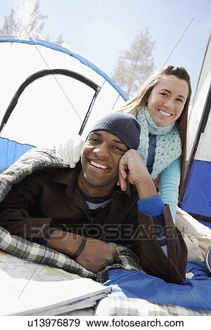 Stock Photo - Young couple sitting by tent at campsite. Fotosearch