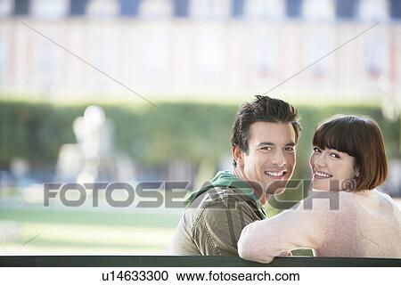 Young couple sitting on bench, head and shoulders, in park View Large Photo Image Stock Image - Young couple sitting on bench, head and shoulders, in park. Fotosearch
