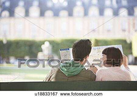 Young couple sitting on bench, looking at map, in park, back view View Large Photo Image Stock Photo - Young couple sitting on bench, looking at map, in park, back view. Fotosearch