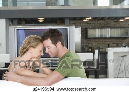 Picture - Young couple sitting on sofa. Fotosearch