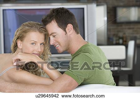Stock Image - Young couple sitting on sofa. Fotosearch