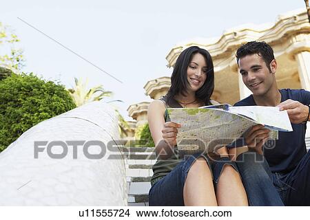 Young couple sitting on stairs reading map, portrait View Large Photo Image Picture - Young couple sitting on stairs reading map, portrait. Fotosearch