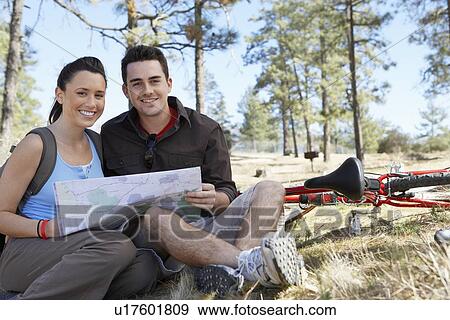 Young couple sitting outdoors reading map, portrait. View Large Photo Image Stock Photo - Young couple sitting outdoors reading map, portrait.. Fotosearch