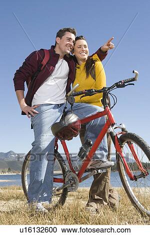 Young couple stand with mountain bike, man pointing View Large Photo Image Stock Image - Young couple stand with mountain bike, man pointing. Fotosearch
