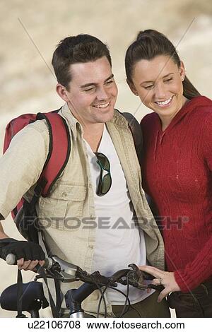Stock Photo - Young couple stand with mountain bike. Fotosearch