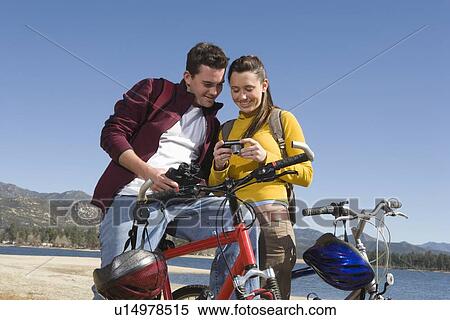 Young couple stand with mountain bike looking at screen of camera View Large Photo Image Stock Photography - Young couple stand with mountain bike looking at screen of camera. Fotosearch