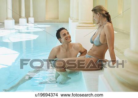 Young couple talking at edge of swimming pool View Large Photo Image Picture - Young couple talking at edge of swimming pool. Fotosearch