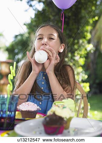 Young girl (10-12) blowing up balloon at birthday party View Large Photo Image Stock Photo - Young girl (10-12) blowing up balloon at birthday party. Fotosearch