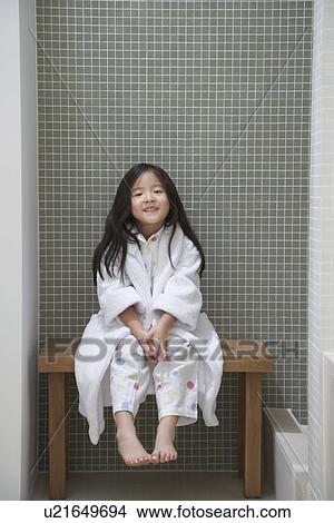Picture - Young Girl wearing bathrobe, Sitting on Bench by Bathtub. Fotosearch