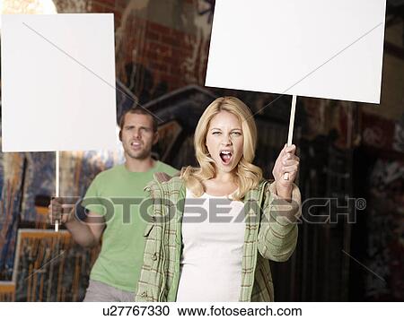Stock Image - Young man and woman holding blank demonstration placards. Fotosearch