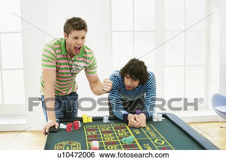 Stock Photograph - Young man celebrating gambling win at roulette table. Fotosearch