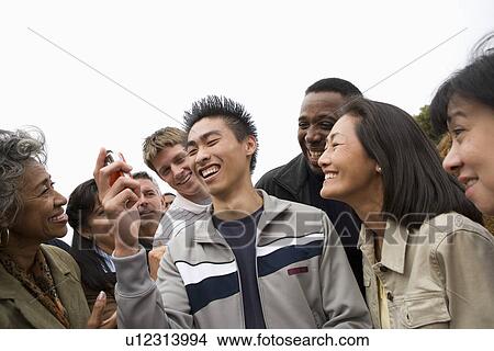 Young man holding mobile phone in crowd View Large Photo Image Picture - Young man holding mobile phone in crowd. Fotosearch