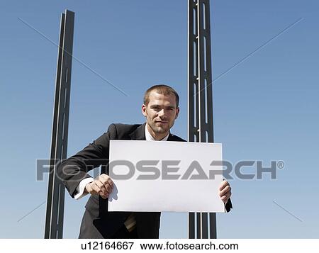 Young man holding sheet of card by concrete pillars View Large Photo Image Stock Photo - Young man holding sheet of card by concrete pillars. Fotosearch