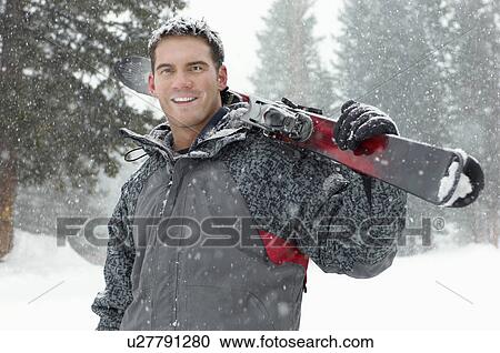 Young man holding skis in snow, half length View Large Photo Image Stock Image - Young man holding skis in snow, half length. Fotosearch