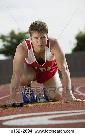 Young man in starting blocks holding relay baton, portrait View Large Photo Image Picture - Young man in starting blocks holding relay baton, portrait. Fotosearch