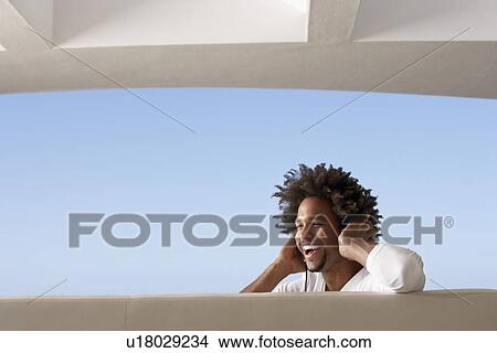Picture - Young man listening to music through headphones, portrait. Fotosearch