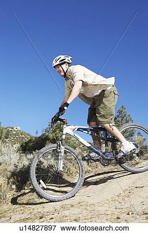 Young man mountain biking down track, side view. View Large Photo Image Stock Photo - Young man mountain biking down track, side view.. Fotosearch