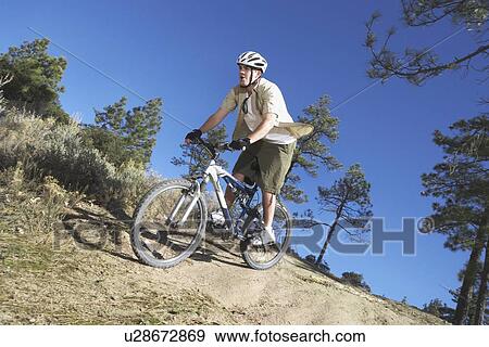 Young man mountain biking through field View Large Photo Image Stock Photo - Young man mountain biking through field. Fotosearch