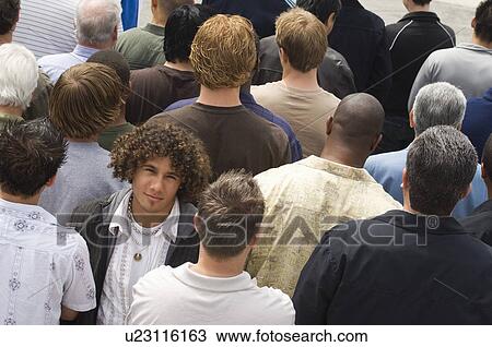 Young man standing in crowd View Large Photo Image Stock Image - Young man standing in crowd. Fotosearch