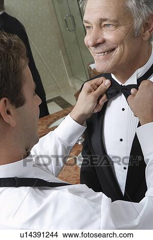 Young man tying middle-aged man's bow tie View Large Photo Image Picture - Young man tying middle-aged man's bow tie. Fotosearch