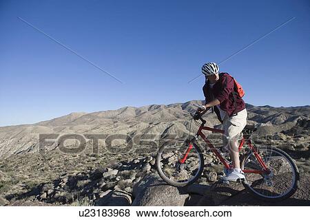 Stock Photo - Young man waits with mountain bike looking back over his shoulder. Fotosearch