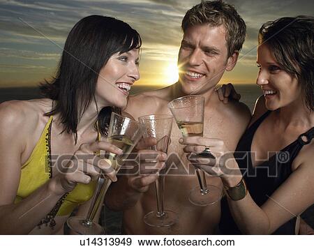 Young people in bathing suits toasting champagne at sunset outdoors View Large Photo Image Stock Photo - Young people in bathing suits toasting champagne at sunset outdoors. Fotosearch