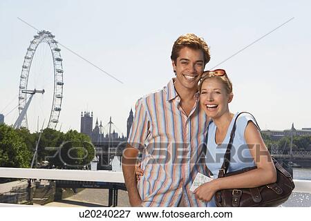 Stock Photo - Young vacationing couple posing by Thames River, portrait. Fotosearch