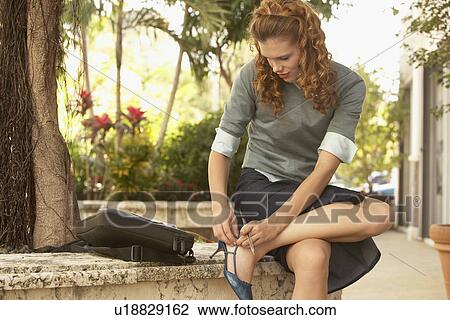 Young woman adjusting shoe in street View Large Photo Image Stock Image - Young woman adjusting shoe in street. Fotosearch