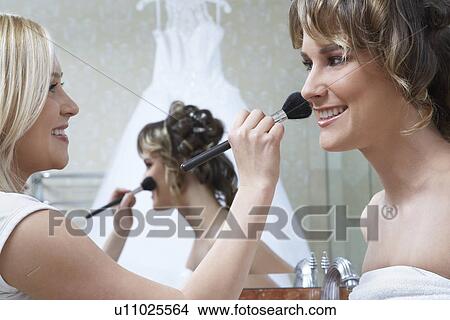 Picture - Young woman applying make-up to bride's face. Fotosearch