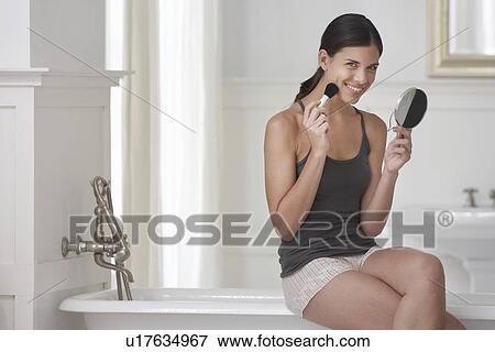 Stock Photo - Young Woman Applying Makeup in Bathroom. Fotosearch
