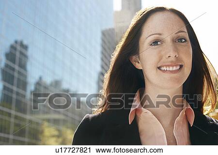 Stock Image - Young woman by office building, portrait. Fotosearch