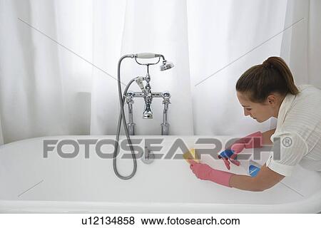 Young woman cleaning bathtub View Large Photo Image Stock Photo - Young woman cleaning bathtub. Fotosearch