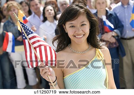 Stock Photo - Young woman holding American flag, portrait. Fotosearch