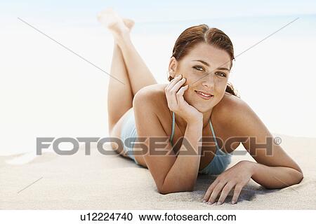 Stock Image - Young woman in bikini lying on beach, close-up. Fotosearch