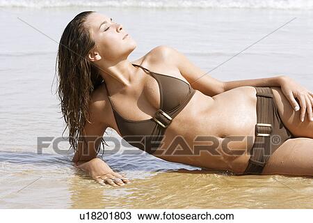 Young woman in bikini lying on beach, close-up View Large Photo Image Stock Image - Young woman in bikini lying on beach, close-up. Fotosearch