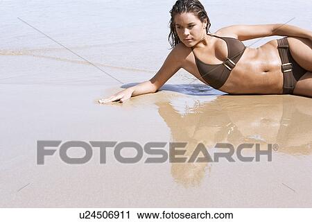 Young woman in bikini lying on beach View Large Photo Image Stock Image - Young woman in bikini lying on beach. Fotosearch