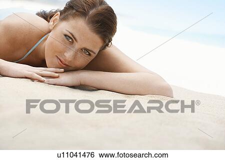 Stock Photograph - Young woman in bikini lying on beach, close-up. Fotosearch